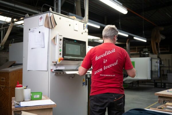 CNC-operator aan de bedieningsconsole van de freesmachine in het atelier van Werco