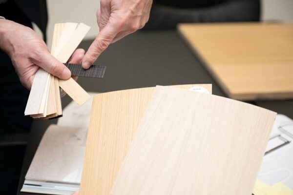 Werco-medewerker toont houtfineer- en paneelstalen boven een bureau