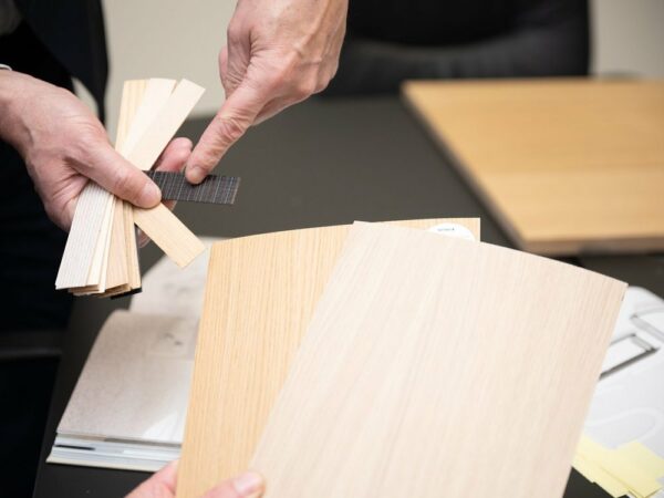 Houtfineer- en paneelstalen bij Werco Werco-medewerker toont houtfineer- en paneelstalen boven een bureau